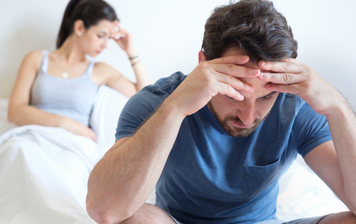 A man and a woman in bed, frustrated with his erectile dysfunction.