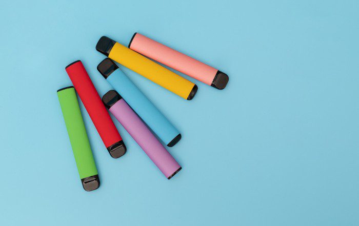 A collection of different coloured vaping devices on a blue background.
